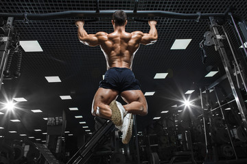 Athlete muscular fitness bodybuilder male model pulling up on horizontal bar