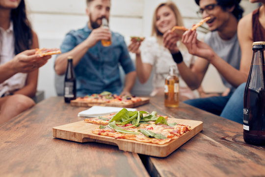 Pizza on table with friends enjoying party