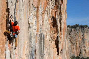 Young man climbing on a limestone wall with wide valley on the background