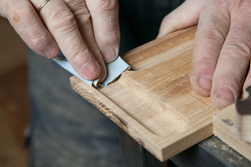 Men sandpaper grinds wood product in a workshop