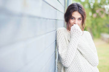 Beautiful shy natural young brunette woman wearing knitted sweater by the house.  Fashion concept.