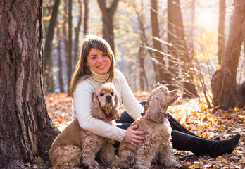 Young beautiful woman and her dog (American Cocker Spaniel) posing in park at fall time 