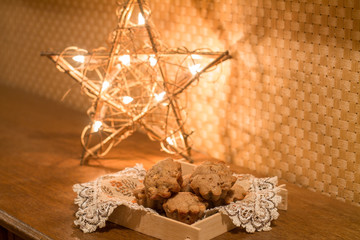 Fototapeta na wymiar Muffins with apples and cinnamon on wood table near Christmas light.