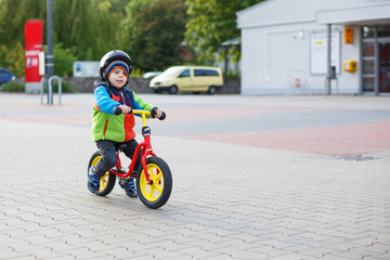 Little toddler boy learning to ride on his first bike 