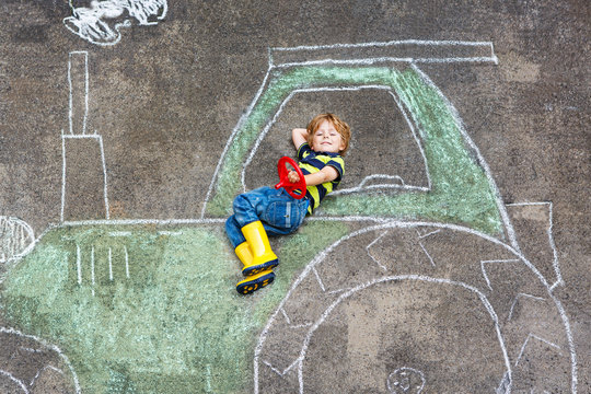 Little boy having fun with tractor picture drawing with chalk