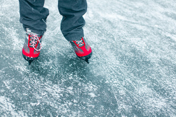 Young woman ice skating outdoors on a pond on a freezing winter day - detail of the legs.
