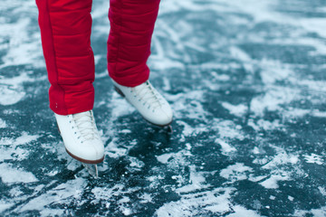Young woman ice skating outdoors on a pond on a freezing winter day - detail of the legs.
