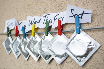  condom and sealed condoms on colorful clothespins. seven days o