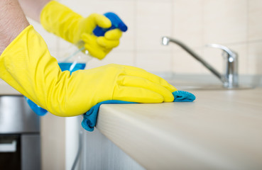 Hands wiping kitchen countertop