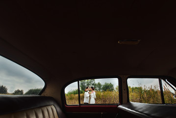 Fototapeta premium unusual view of stylish bride and happy groom through red retro