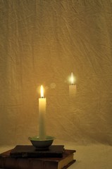 Burning candle in the dark and old books
