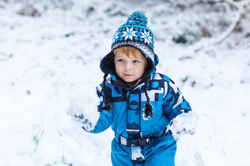 Happy child having fun with snow in winter