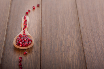 Pomegranate grains on a wooden spoon