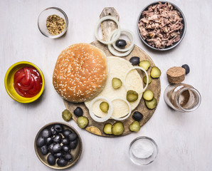 Fototapeta na wymiar ingredients for homemade burger, tuna, bun, sauce, olives, spices on wooden rustic background top view border, place for text