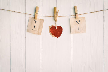 Two blank old paper and red heart hanging. On white wooden backg