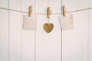 Two blank old paper and brown heart hanging. On white wooden bac