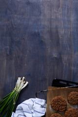 Vegetarian falafel chickpea patties on backing tray with green onion, wood background. Copy space, top view.