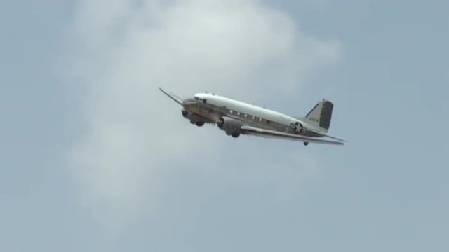 Historic Douglas C-47 Skytrain military transport plane flying in cloudy sky.  Also known as the Dakota in the UK.  Recorded in 4K, ultra high definition.