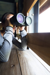 Woman looking though binocular at wooden house