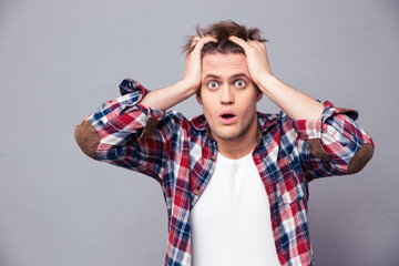 Shocked dazed young man holding head with both hands