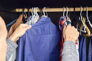 young man choosing a shirt from a clothes rack