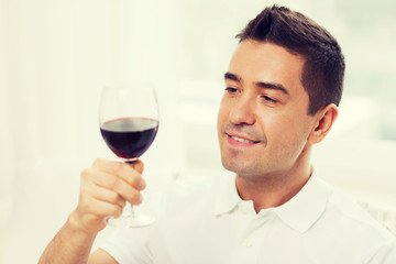 happy man drinking red wine from glass at home