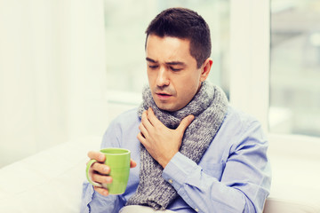 ill man with flu drinking tea and coughing at home