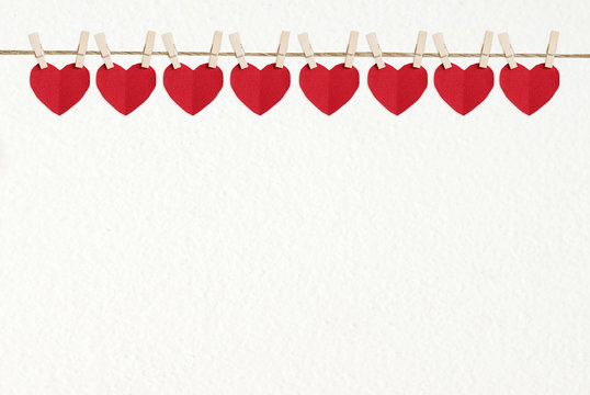 Red heart shape fabric hanging on white wall background