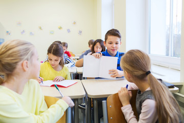 group of school kids writing test in classroom