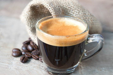 Shot of Espresso with beans on wood