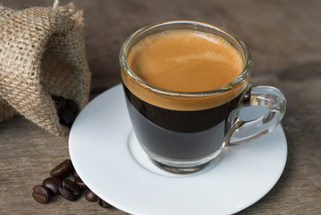 Shot of Espresso with beans on wood