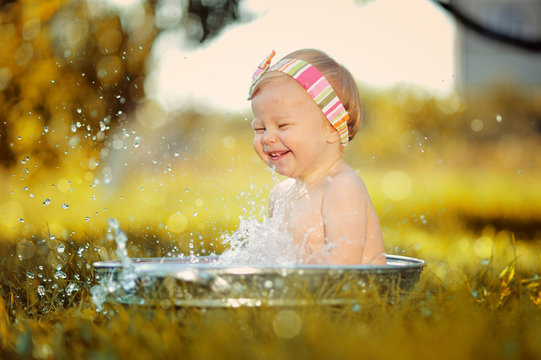 Маленький ребенок играет в тазике с водой