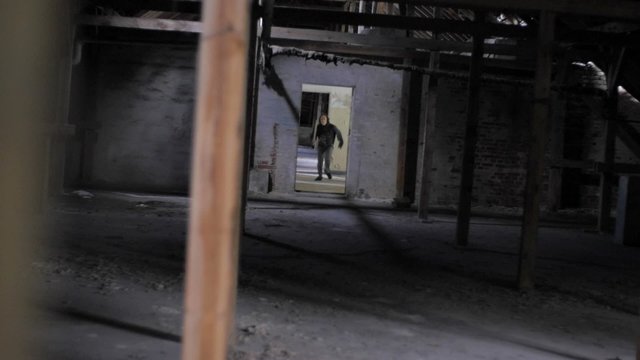 Slow motion of vandal with mask and bar running in abandoned building