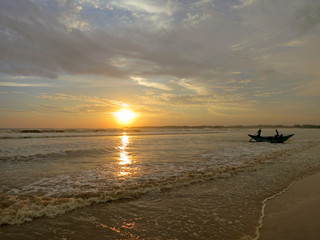 Sunset beach with fisherman boat silhouette in water, Sri Lanka