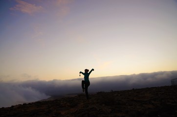 Woman in the crane position on top of a mountain in Oman during sunset