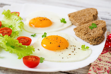 Breakfast on Valentine's Day - fried eggs and bread in the shape of a heart and fresh vegetables.