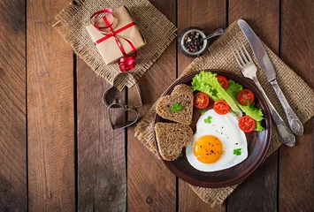 Photo sur Aluminium Oeufs sur le plat Petit-déjeuner le jour de la Saint-Valentin - œufs au plat et pain en forme de cœur et légumes frais. Vue de dessus