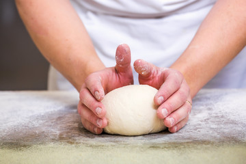 Close-up the hand of a baker kneading and shaping dough