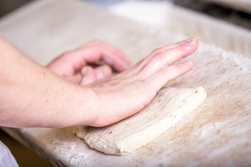 Obraz na płótnie Canvas Close-up the hand of a baker kneading and shaping dough