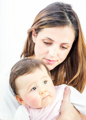 close-up of a smiling young woman with her baby on white background