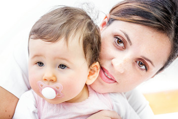 close-up of a smiling young woman with her baby on white background