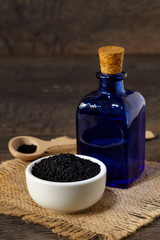 Nigella sativa (Black cumin) on wooden spoon and essential oil. 