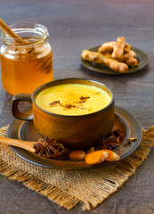 Healthy drink made from turmeric roots, exotic spices with milk and honey