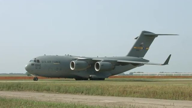 Wide view of Boeing C-17 Globemaster military transport taxiing at airfield. Used by the United States Air Force and developed by McDonnell Douglas.  Control tower in background.