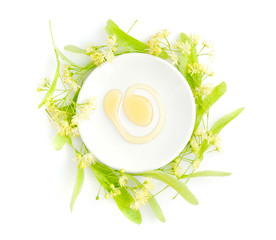 Honey with flowers of linden on white saucer, view from above