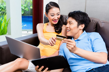 Asian couple shopping online in internet with laptop