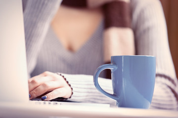 Cup near a woman with notebook computer