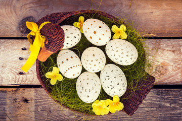 Obraz na płótnie Canvas Beautiful unique Easter eggs in a basket, on wooden background