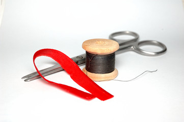 Scissors and a skein of black thread on white background