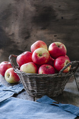Old basket with apples on wooden background